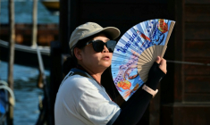 Une touriste utilise un éventail pour se rafraîchir, place Saint-Marc, à Venise, lors d'un épisode de canicule en Europe, le 26 juin 2026  ( AFP / Stefano RELLANDINI )