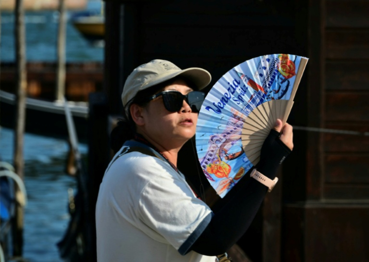 Une touriste utilise un éventail pour se rafraîchir, place Saint-Marc, à Venise, lors d'un épisode de canicule en Europe, le 26 juin 2026  ( AFP / Stefano RELLANDINI )