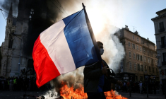 Un manifestant avec un drapeau français devant un feu, le 17 octobre 2026 à Marseille ( AFP / Thibaud MORITZ )