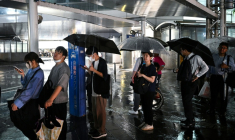 Des personnes attendent un taxi à la station de métro de Chiba, dans la ville de Chiba à l'est de Tokyo, le 13 août 2026, alors que de fortes pluies s'abattaient sur la région ( AFP / Philip FONG )