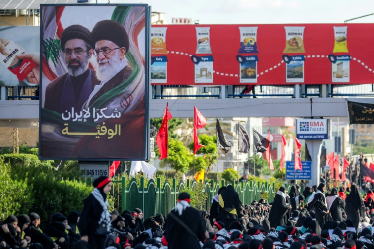 Une affiche représentant le défunt ayatollah Ali Khamenei et son fils l'actuel guide suprême iranien Mojtaba Khamenei est exposée alors que des fidèles chiites se rassemblent pour une procession funèbre, dans la banlieue sud de Beyrouth, le 26 juin 2026 ( AFP / ibrahim AMRO )