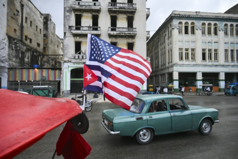 Un drapeau cubain et un drapeau américain flottent sur le toit d'un tricycle à La Havanne, le 30 janvier 2026  ( AFP / YAMIL LAGE )