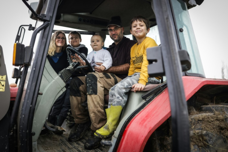 L'agriculteur Jérôme Caze, sa femme Sandra (g) et leurs trois enfants, Nino, Elie et Lialas, dans la cabine du tracteur dans leur ferme à Meilhan-sur-Garonne, le 24 octobre 2024 dans le Lot-et-Garonne ( AFP / Thibaud MORITZ )