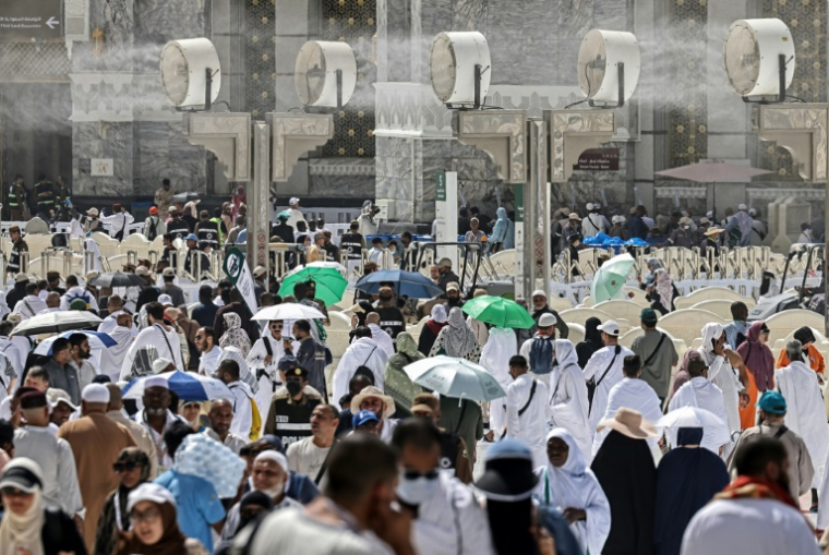 Des pèlerins passent sous des brumisateurs dans la chaleur accablante de La Mecque, le 22 mai 2026. ( AFP / Zain JAAFAR )