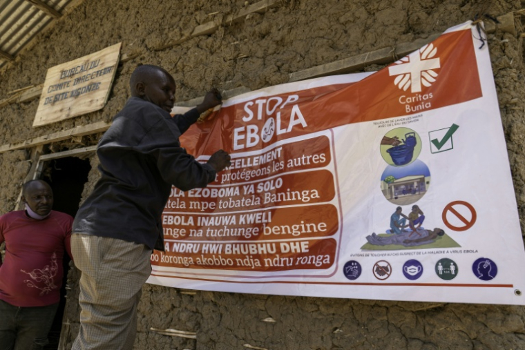 Un homme accroche une banderole de sensibilisation au virus Ebola dans le camp pour personnes déplacées de Kigonze à Bunia, dans l'est de la République démocratique du Congo, le 28 mai 2026 ( AFP / Glody MURHABAZI )