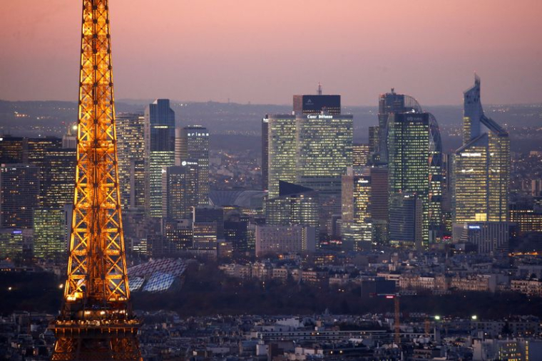Vue générale de la Tour Eiffel illuminée et de la ligne d'horizon du quartier d'affaires de La Défense, la nuit, à Paris