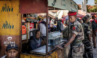 Au lendemain de la prise de pouvoir, un soldat de l'unité Capsat discute avec une vendeuse près de sa base militaire à Antananarivo, le 15 octobre 2025 ( AFP / Luis TATO )
