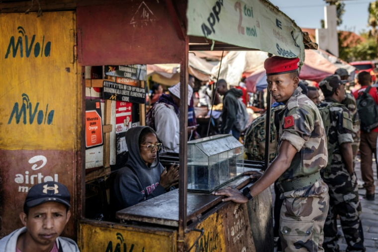 Au lendemain de la prise de pouvoir, un soldat de l'unité Capsat discute avec une vendeuse près de sa base militaire à Antananarivo, le 15 octobre 2025 ( AFP / Luis TATO )