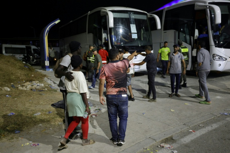 Des membres des forces de l'ordre marocaines acheminent par bus vers leurs villes d'origine des personnes qui avaient pénétré illégalement dans l'enclave espagnole de Ceuta, sur la côte nord du Maroc, le 1er août 2026 à Fnideq  ( AFP / Abdel Majid BZIOUAT )