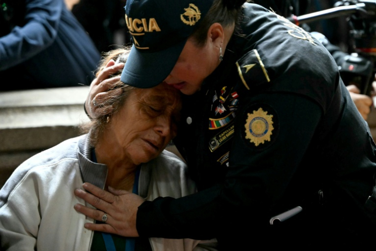 Une policière réconforte une proche d'un officier tué lors d'une cérémonie au siège du ministère de l'Intérieur, à Guatemala, le 19 juillet 2026 ( AFP / JOHAN ORDONEZ )