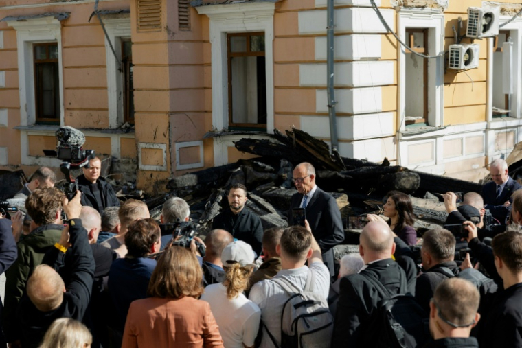 Le président ukrainien Volodymyr Zelensky (CG) et le chancelier allemand Friedrich Merz (CD) lors d'une visite du bâtiment endommagé de l'Académie des sciences de Kiev, le 4 octobre 2026  ( AFP / Tetiana DZHAFAROVA )