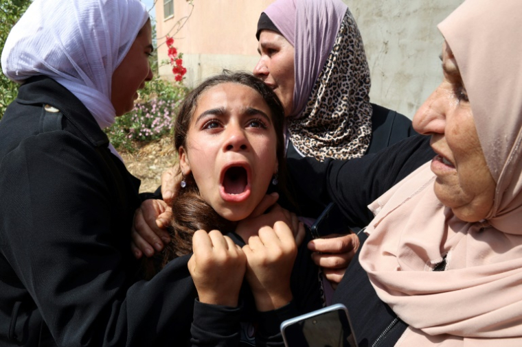 Des Palestiniennes consolent une fillette aux funérailles d'un proche, tué dans un raid israélien à Tammun, en Cisjordanie occupée, le 15 mai 2025 ( AFP / Zain JAAFAR )
