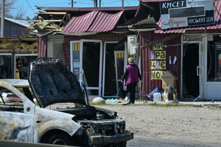 Une femme passe devant des magasins endommagés sur le site d’une frappe de missile russe dans la ville de Merefa, dans la région de Kharkiv, le 4 mai 2026 ( AFP / SERGEY BOBOK )