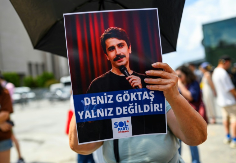 Une personne tient une pancarte de soutien à l'humoriste turc Deniz Goktas, sur laquelle on peut lire "Deniz Goktas n'est pas seul", lors d'une manifestation devant le palais de justice de Çağlayan, à Istanbul, le 3 juillet 2026 ( AFP / Yasin AKGUL )