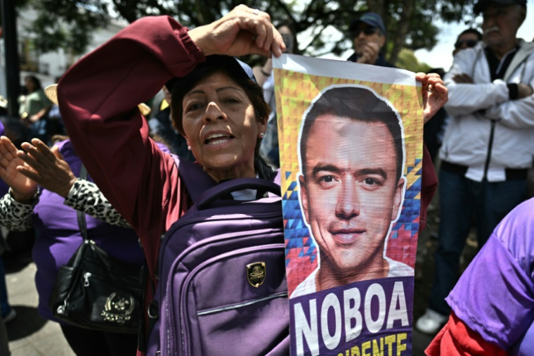 Une partisane du président réélu Daniel Noboa tient un portrait de celui-ci, le 14 avril 2025 à Quito ( AFP / Luis ACOSTA )