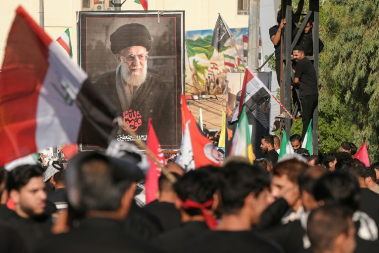Des personnes en deuil rassemblées près d'un portrait de l'ancien guide suprême iranien Ali Khamenei, lors de son cortège funèbre à Nadjaf, le 8 juillet 2026 en Irak ( AFP / Qassem al-KAABI )