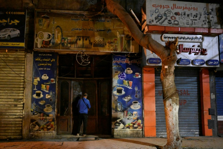 Un commerçant ferme sa boutique dans le centre-ville du Caire en applicaton du couvre-feu, le 2 avril 2026 en Egypte ( AFP / Khaled DESOUKI )