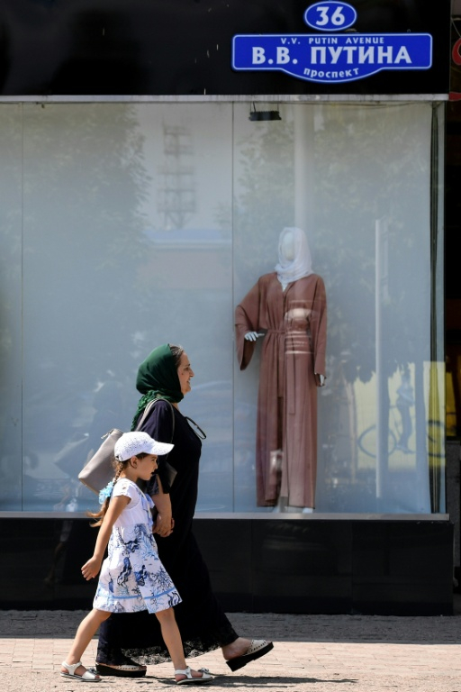 Une femme et une enfant passent devant une boutique vendant des vêtements à Grozny en Tchétchénie, le 26 juillet 2017  ( AFP / Kirill KUDRYAVTSEV )