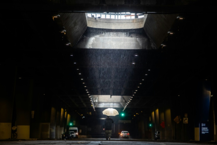 Un homme se promène à Los Angeles pendant les fortes pluies, le 24 décembre 2025 ( AFP / Apu GOMES )