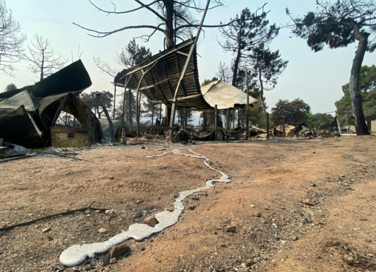 Une traînée de métal en fusion provenant d’un véhicule calciné après un incendie de forêt au camping Pantano de Burguillo, à El Barraco, à 100 kilomètres à l’ouest de Madrid, le 27 juillet 2026 ( AFP / Roland LLOYD PARRY )