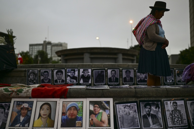 Une personne se tient à côté de photographies de victimes de crimes imputés à l'Etat péruvien, lors d’une veillée devant le Palais de Justice à Lima, le 27 juillet 2026 ( AFP / Ernesto BENAVIDES )