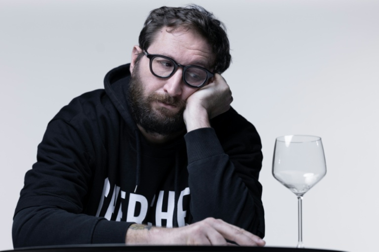 L'auteur de BD Terreur Graphique à côté d'un verre vide à l'occasion de la sortie de son livre relatant ses 25 ans d'alcoolisme et son combat pour la sobriété, le 13 janvier 2026 à Paris ( AFP / Joel Saget )