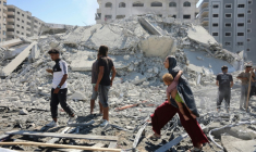 Une Palestinienne porte un enfant dans ses bras au milieu des décombres près d'une tour qui s'est effondrée quelques instants après avoir été touchée par des frappes israéliennes à Gaza-ville, le 10 septembre 2025 ( AFP / Omar AL-QATTAA )