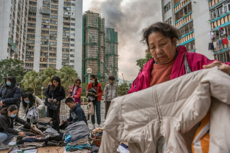 Des habitants trient des vêtements qui leur ont été donnés après qu'un important incendie a ravagé plusieurs immeubles d'appartements du complexe résidentiel Wang Fuk Court à Hong Kong, le 27 novembre 2025 ( AFP / Dale DE LA REY )