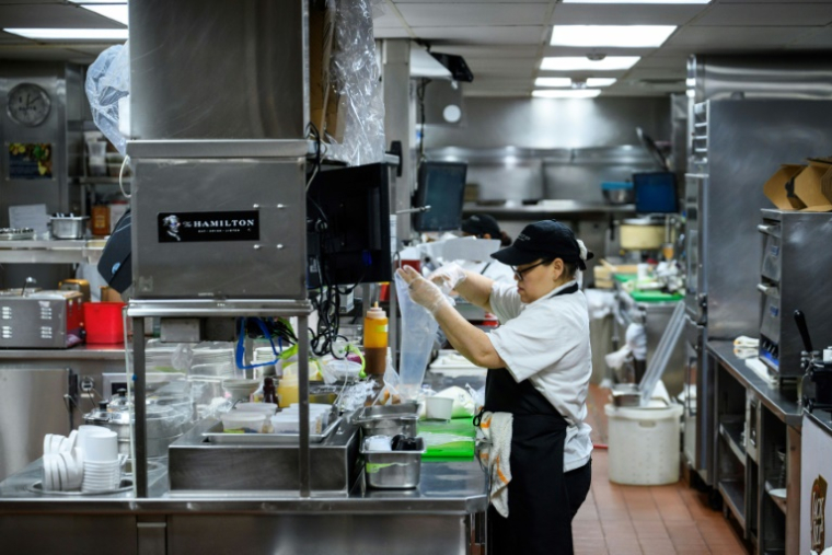 Des employés travaillent dans la cuisine du restaurant The Hamilton pendant le déjeuner à Washington, le 2 juillet 2025 ( AFP / Drew ANGERER )