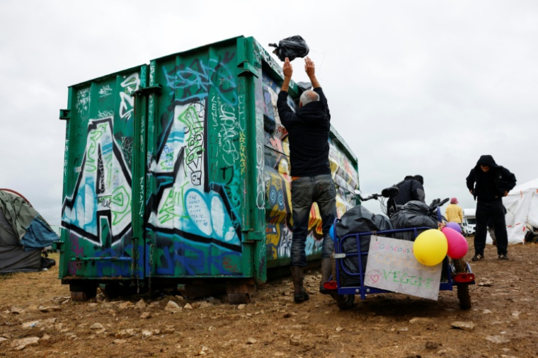 Un participant nettoie le site militaire où s'est déroulée une rave party "teknival" à Cornusse, près de Bourges, le 4 mai 2026 dans le Cher ( AFP / Kenzo TRIBOUILLARD )