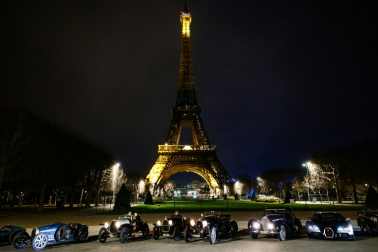 Des voitures de collection Bugatti sur le champ de Mars, devant la tour Eiffel, durant la parade nocturne pour les 50 ans de Rétromobile, le 26 janvier 2026, à Paris ( AFP / Dimitar DILKOFF )