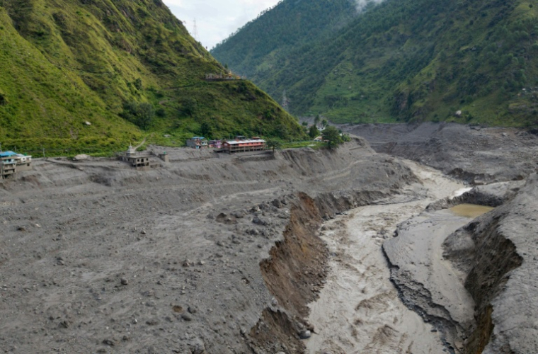 Vue aérienne d'un torrent d'eau boueuse déferlant près des habitations après des crues soudaines, près de la frontière entre le Népal et la Chine, au niveau du village de Syabrubesi, le 31 août 2026 au Népal ( AFP / Prabin Ranabhat  )