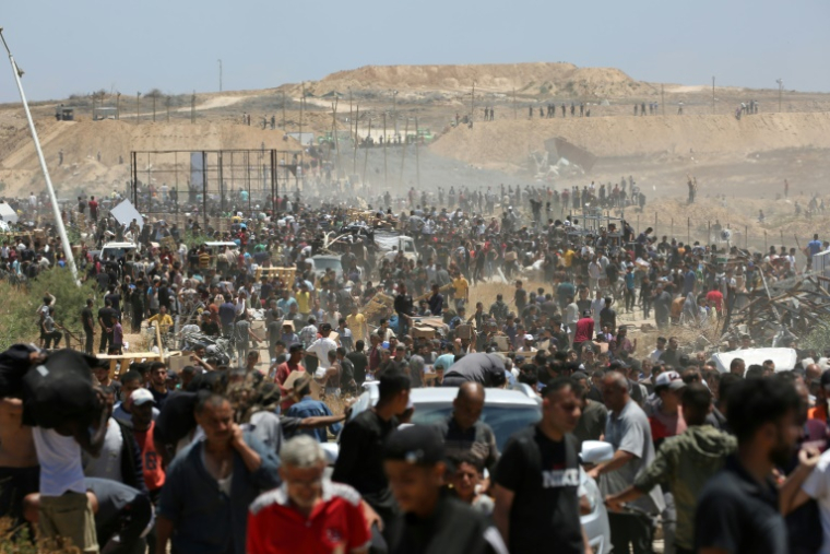 Des Palestiniens déplacés transportent des sacs d'aide, de retour d'un centre de distribution de la GHF dans le centre de la bande de Gaza, le 29 mai 2025 ( AFP / Eyad BABA )