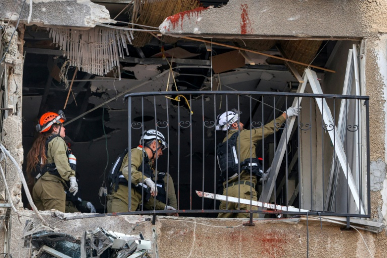 Les forces de sécurité et secouristes israéliens inspectent un immeuble frappé à Bnei Brak, près de Tel-Aviv, le 15 mars 2026  ( AFP / Jack GUEZ )