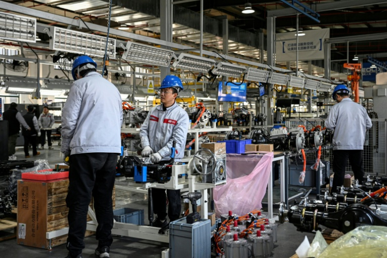 Des ouvriers travaillent sur une ligne de production de l'usine Neolix qui fabrique de petits véhicules utilitaires autonomes pour le transport de colis en ville, le 4 décembre 2025 à Yancheng dans la province chinoise du Jiangsu  ( AFP / Jade GAO )