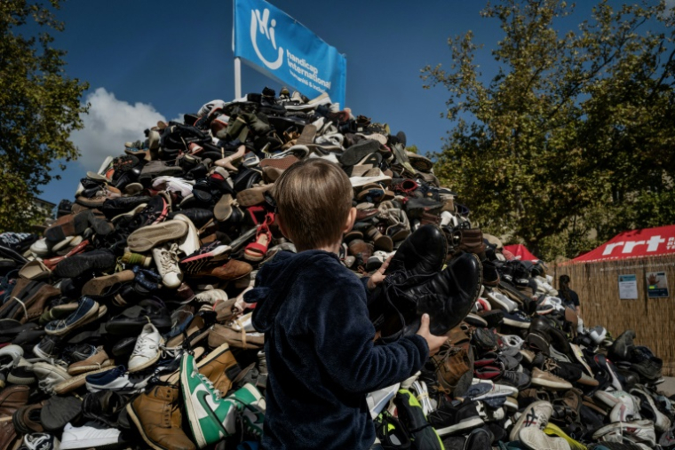 Un enfant jette une paire de chaussures à l'occasion du 30e anniversaire de la pyramide de chaussures de Handicap international (HI), le 27 septembre 2025 à Lyon ( AFP / JEFF PACHOUD )