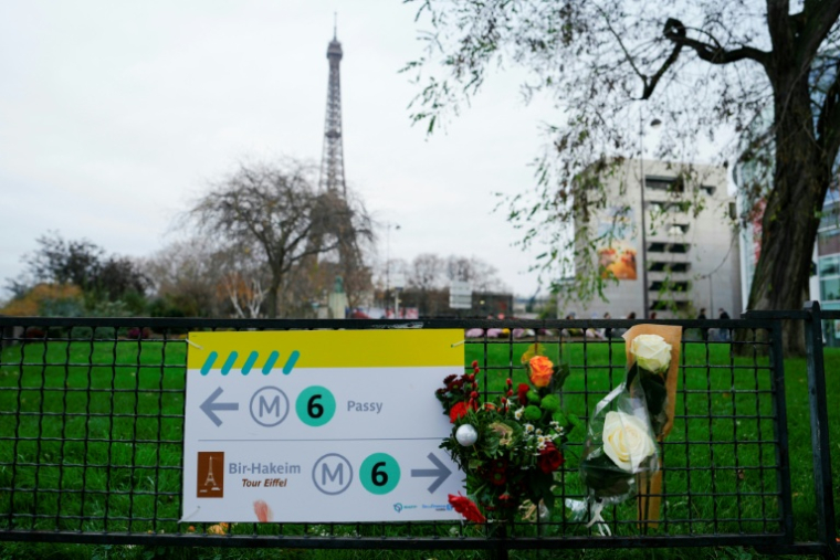 Des fleurs déposées sur une barrière près de la tour Eiffel le 3 décembre 2023 après l'attaque au couteau qui a coûté la vie à un touriste, à Paris ( AFP / Dimitar DILKOFF )