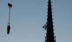 Une grue soulève l'une des 16 statues géantes d'apôtres pour la replacer sur sa base au pied de la flèche de la cathédrale Notre-Dame de Paris, le 23 juin 2025 ( AFP / GEOFFROY VAN DER HASSELT )