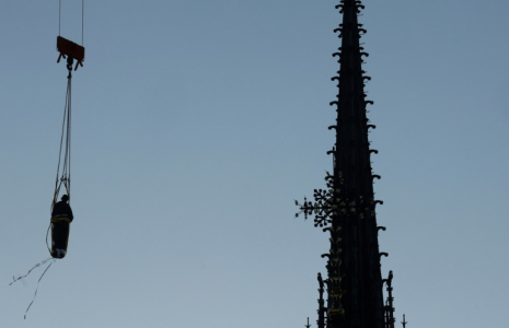 Une grue soulève l'une des 16 statues géantes d'apôtres pour la replacer sur sa base au pied de la flèche de la cathédrale Notre-Dame de Paris, le 23 juin 2025 ( AFP / GEOFFROY VAN DER HASSELT )