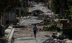 Une personne marche le 25 septembre 2025 parmi les décombres dans une rue du quartier de Delmas 30 à Port-au-Prince, en Haïti, quartier ayant subi plusieurs attaques de gangs ( AFP / Clarens SIFFROY )