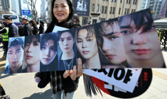 Une fan de BTS montre les photos des sept membres du groupe de K-pop, le 21 mars 2026 à Séoul ( AFP / Jung Yeon-je )