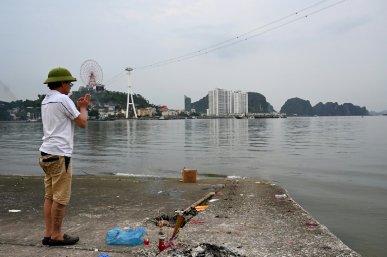 Un homme prie pour les victimes du naufrage d'un bateau de tourisme qui a fait au moins 35 morts dans la province vietnamienne côtière de Quang Ninh, le long de la Baie d'Halong, le 20 juillet 2025 ( AFP / Nhac NGUYEN )