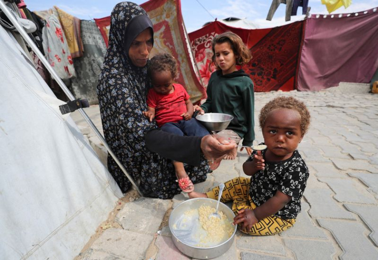 Une Palestinienne nourrit ses enfants devant la tente qui les abrite, à Gaza