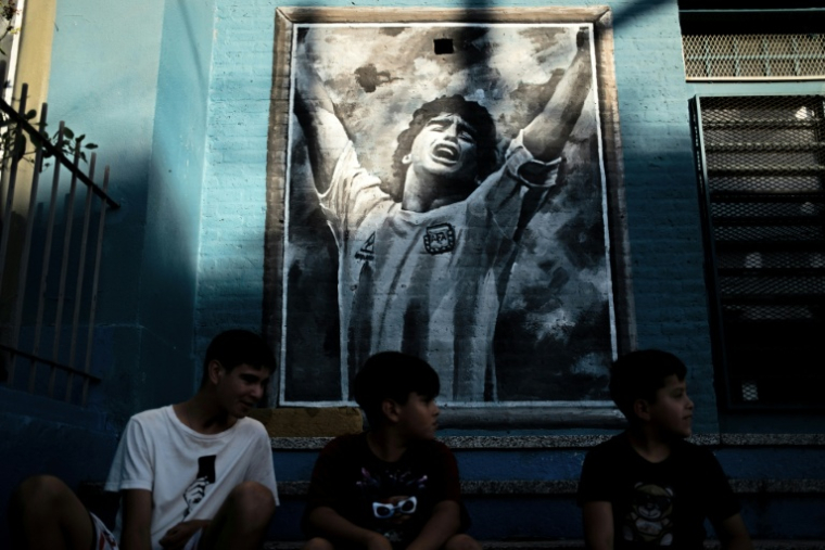 Des enfants devant une fresque murale représentant la star de football Diego Maradona, aujourd’hui décédé, dans son quartier natal de Villa Fiorito, dans la province de Buenos Aires, en Argentine, le 9 avril 2026 ( AFP / TOMAS CUESTA )
