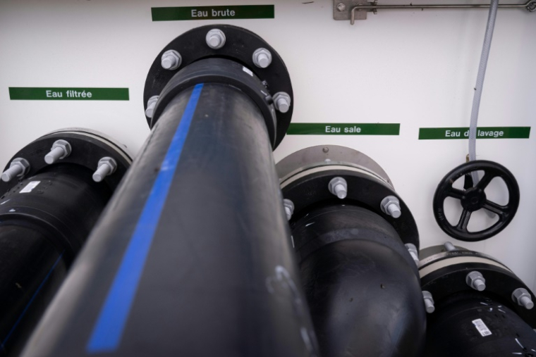 Des conduites d'eau pour l'eau filtrée, l'eau brute, l'eau sale et l'eau de nettoyage sortent d'une unité mobile de traitement de la pollution de l'eau par les PFAS à Bartenheim, le 4 septembre 2025 dans le Haut-Rhin ( AFP / SEBASTIEN BOZON )