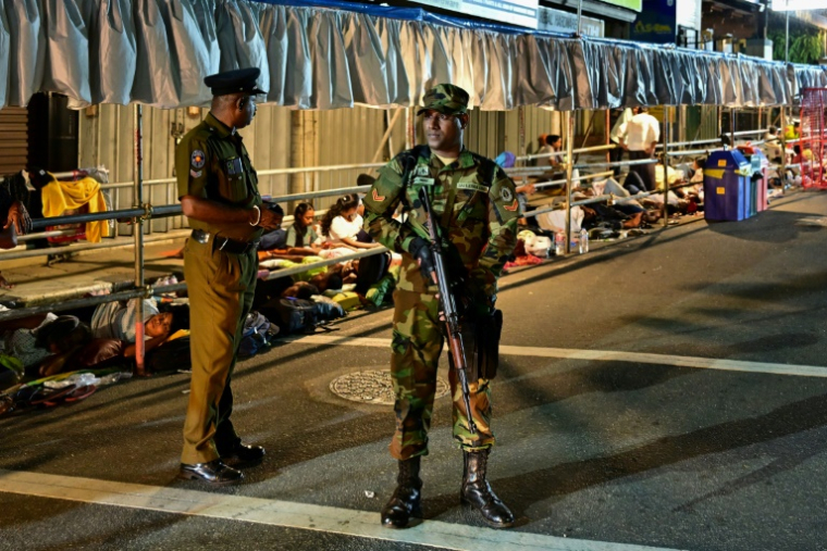 Des pèlerins campent sur le trottoir sous la surveillance de soldats dans l'attente d'admirer une relique de Bouddha le 18 avril 2025 à Kandy au Sri Lanka ( AFP / Ishara S. KODIKARA )