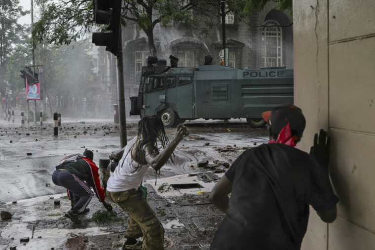 Des manifestants lancent des pierres sur un canon à eau de la police anti-émeute lors des commémorations du premier anniversaire de la prise du Parlement, le 25 juin 2025 à Nairobi, au Kenya ( AFP / Tony KARUMBA )