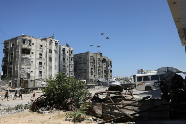 Des Palestiniens courent vers un lieu où des colis d'aide humanitaire sont largués par un avion militaire près de Jabalia, dans le nord de la bande de Gaza, le 20 août 2025 ( AFP / BASHAR TALEB )