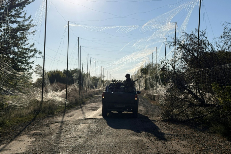 Un soldat de la 141e brigade mécanisée autonome ukrainienne se déplace à bord d'un pick-up sous le filet anti-drones dans le village de Prosyana, dans la région de Dnipropetrovsk, le 2 octobre 2026 ( AFP / Darya Nazarova (STR Zaporizhzhia) )