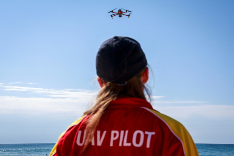 La secouriste Eliza Heys pilote son drone au large d'une plage à Sydney, le 1er octobre 2025 ( AFP / DAVID GRAY )